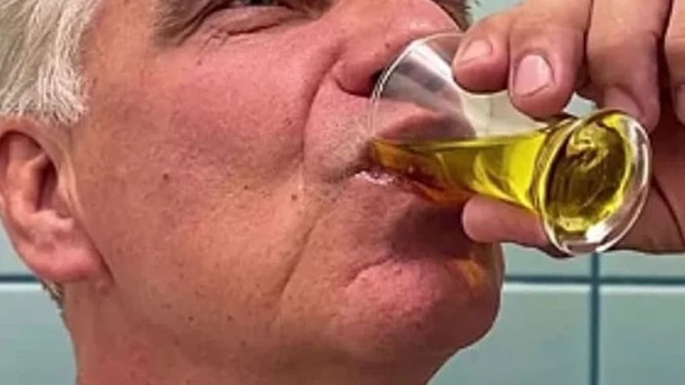 Homem a tomar um gole curto de azeite ou digestivo no fim da refeição