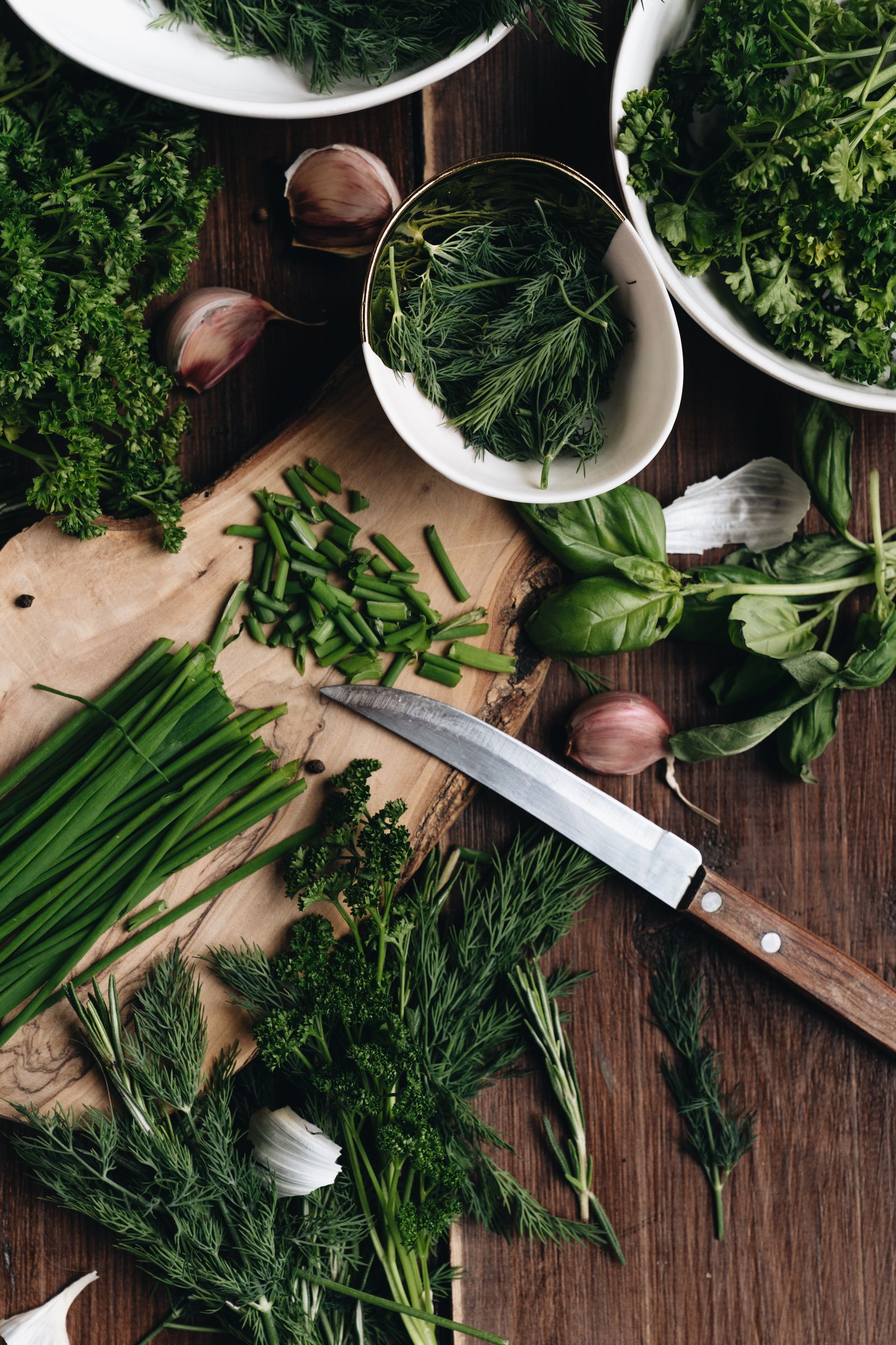 Ervas frescas e legumes sobre uma tábua de madeira