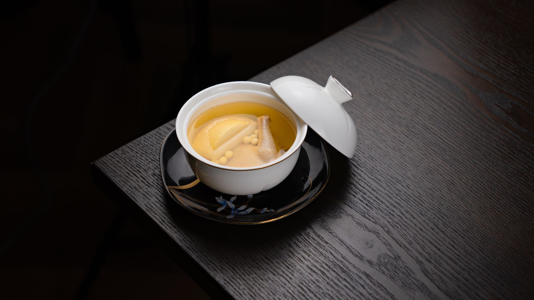 Tigela de caldo quente numa mesa escura, à noite